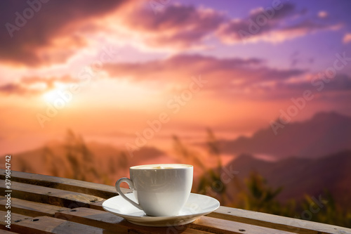 Morning cup of coffee with mountain background at sunrise.