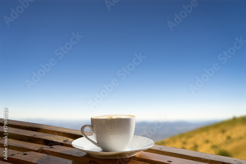 Morning cup of coffee with mountain background at sunrise.