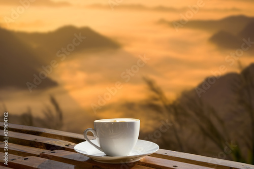 Morning cup of coffee with mountain background at sunrise.