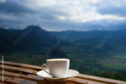 Morning cup of coffee with mountain background at sunrise.