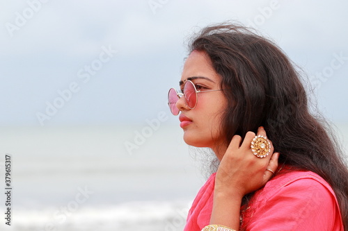 A portrait head shot of a beautiful young Indian woman standing alone on the shores of Chennai, profile view