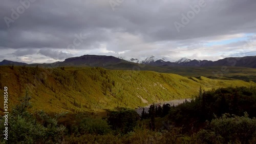 Time lapse: sensational golden hour scene above burwash green uplands, amphitheater alpine meadow and snow covered mountain range in Kluane national park in background on sunny day, Canada, aerial photo