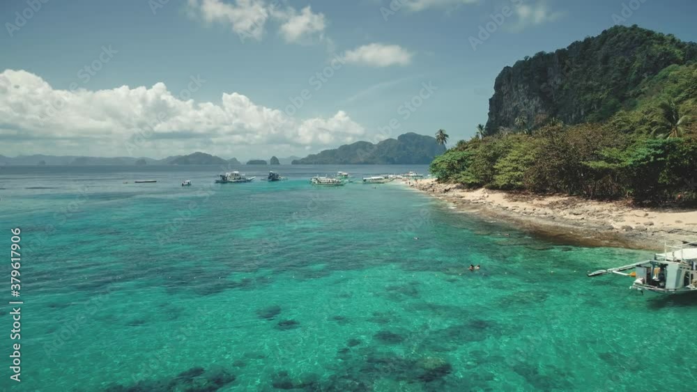 Ocean sand coast with vessels aerial timelapse. Boats and ship at shallow azure water. People rest on sandy beach. Asia tourist landmark on Palawan island, El Nido, Philippines, Asia Ocean sand coast with vessels aerial timelapse. Boats and ship at shallow azure water. People rest on sandy beach. Asia tourist landmark on Palawan island, El Nido, Philippines, Asia