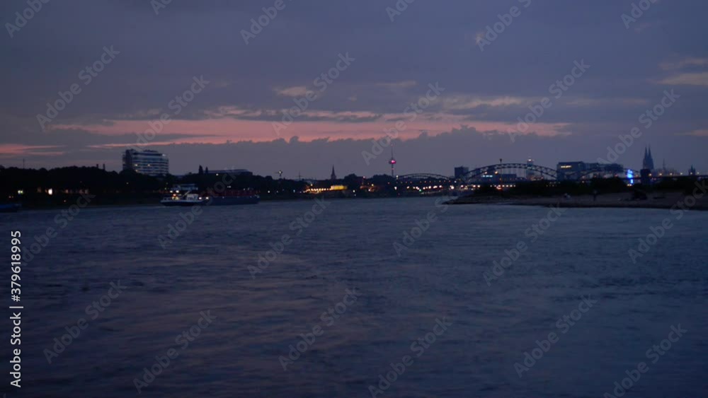 Evening in Cologne, Germany, the rhine river, a cargo ship and the panorama of the city Evening in Cologne, Germany, the rhine river, a cargo ship and the panorama of the city