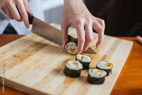 Female chef cutting sushi in the kitchen
