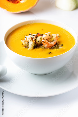 Diet pumpkin soup with shrimp, crouton, turmeric and greens. Healthy food. White background.