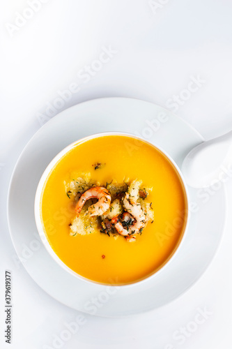 Diet pumpkin soup with shrimp, crouton, turmeric and greens. Healthy food. White background.