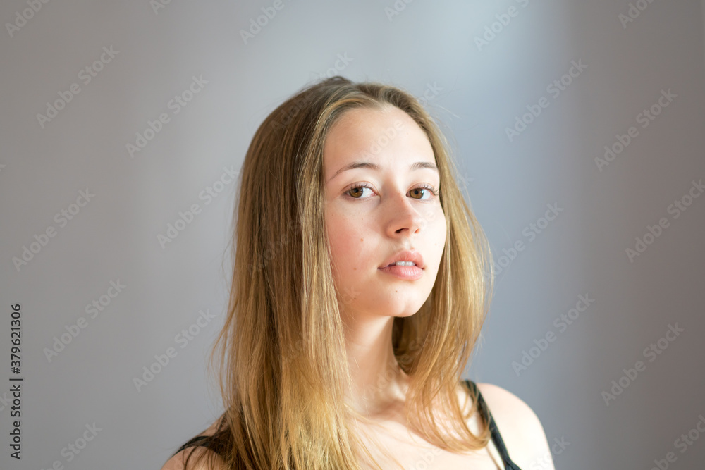Fototapeta premium Portrait of a cute teenage girl wearing a black camisole posing looking at the camera on a grey background