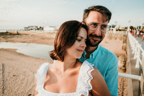 .Young pregnant couple taking pictures on the beach at sunset during their holidays. Lifestyle. Pregnancy