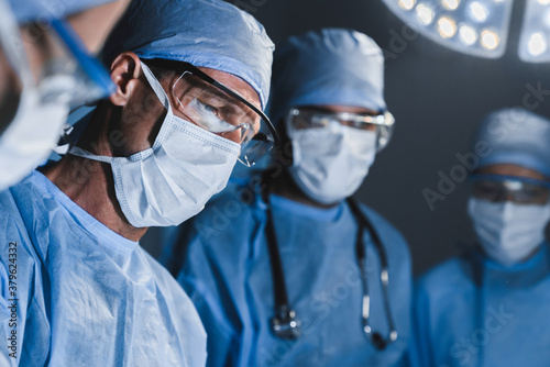 Bild auf Leinwand Concentrated surgeons operating patient in operating theatre