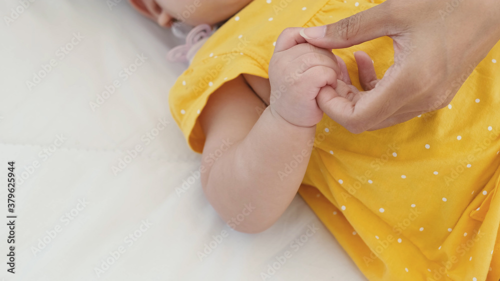 Close up of asian mother holding her newborn baby's hand on the bed. Close up of asian mother holding her newborn baby's hand on the bed.