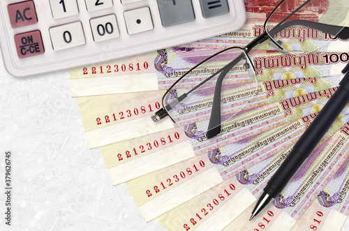 100 Cambodian riels bills fan and calculator with glasses and pen. Business loan or tax payment season concept photo