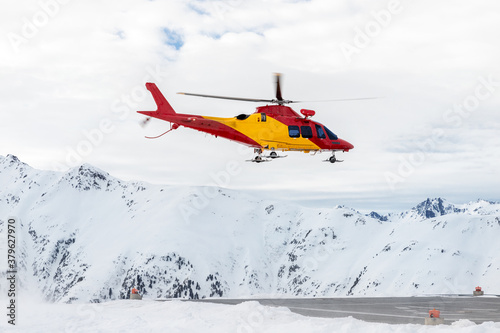 Tableau sur toile Mountain ski life rescue medic helicopter taking-off from station helipad to search injured skiers and help at accident