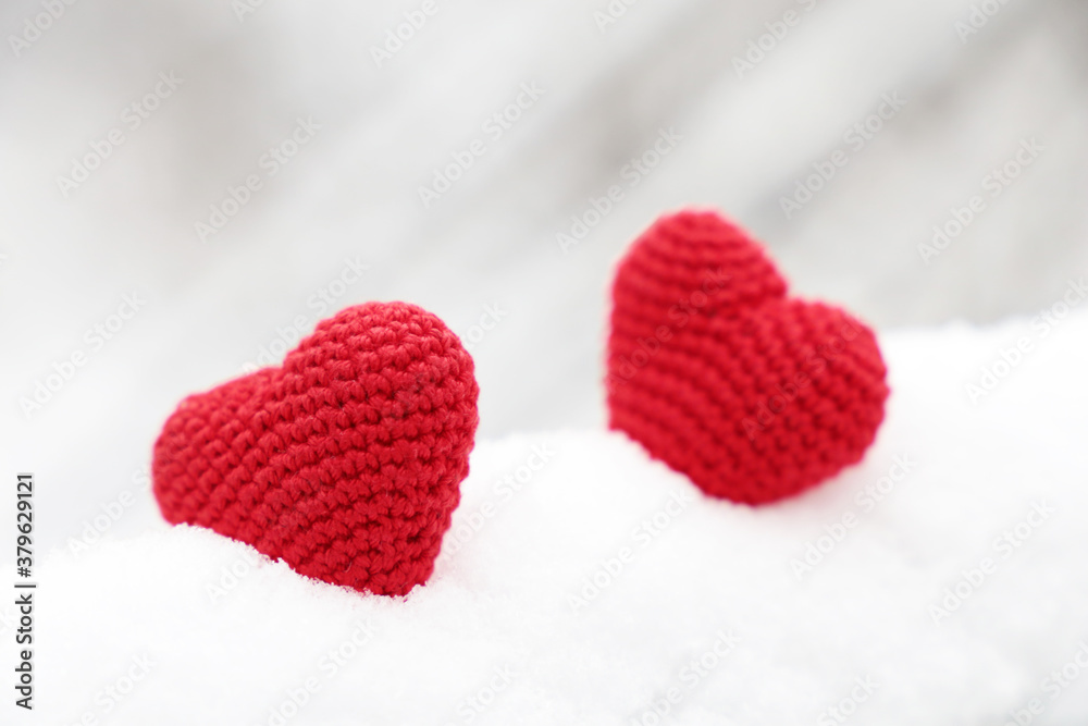 Fototapeta premium Valentines hearts, greeting card, two red knitted symbols of love in the snow. Background for Christmas holiday, celebration or winter weather