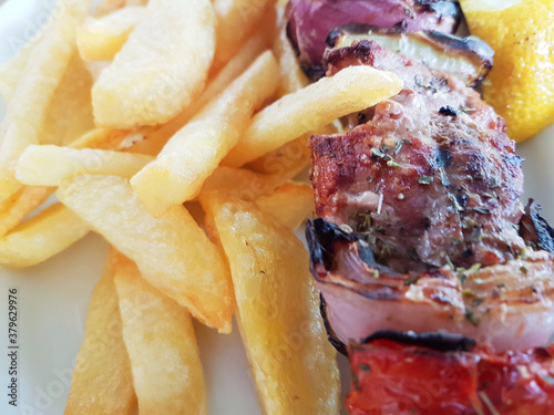 meat called souvlaki and potatoes with lemon in plate photo