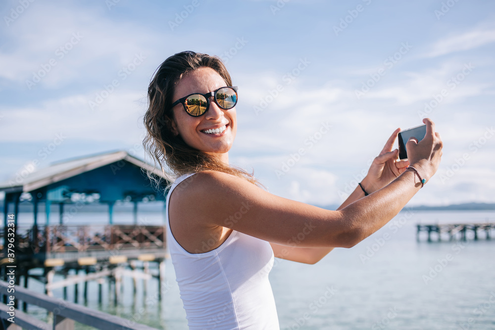Happy adult woman photographing with smartphone on pier