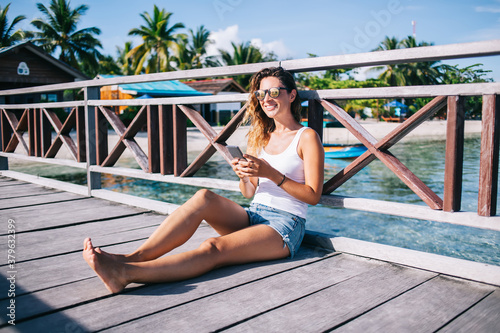 Beautiful adult woman with smartphone in hands on pier
