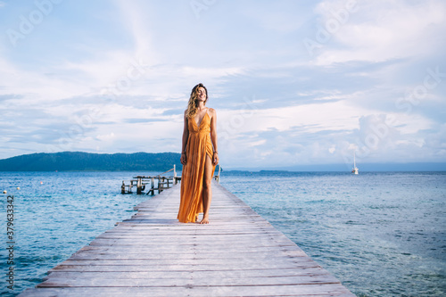 Young beautiful blonde in yellow dress standing on wooden pier © BullRun
