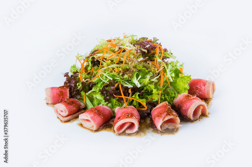 Pan Asian salad with tuna Tataki fillet, herb salad mix  isolated on white background. Side view of fresh fish salad with carrot slices and Matsuhisa sauce Restaurant menu dish isolation photo