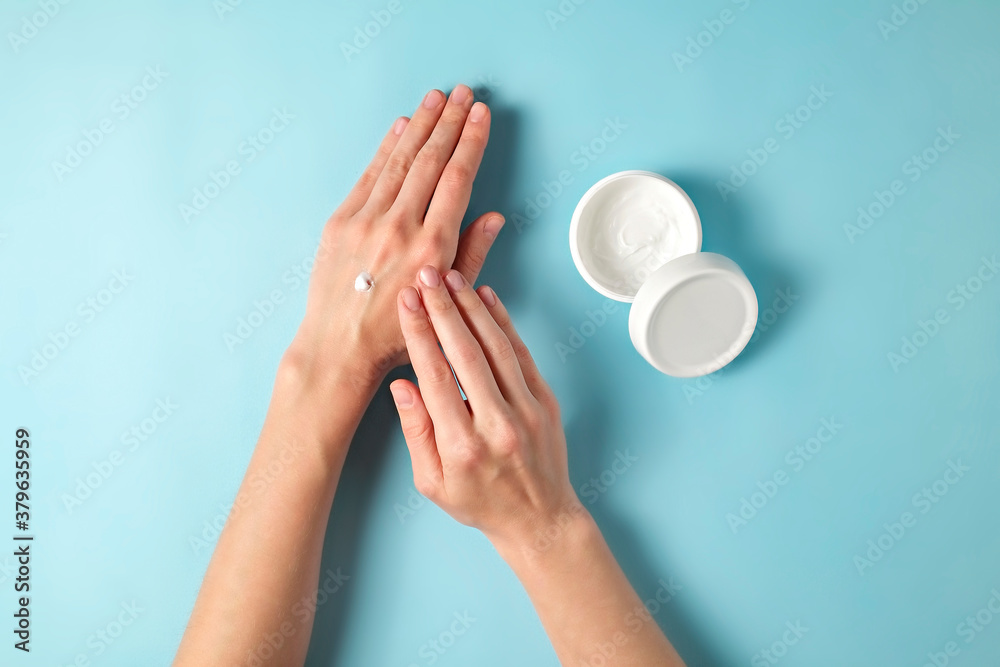 Revitalizing hand cream for healing and recovery after excessive use of soap and disinfectants. Young woman applying moisturizing lotion. Copy space, close up, pink background, flat lay, top view. Revitalizing hand cream for healing and recovery after excessive use of soap and disinfectants. Young woman applying moisturizing lotion. Copy space, close up, pink background, flat lay, top view.