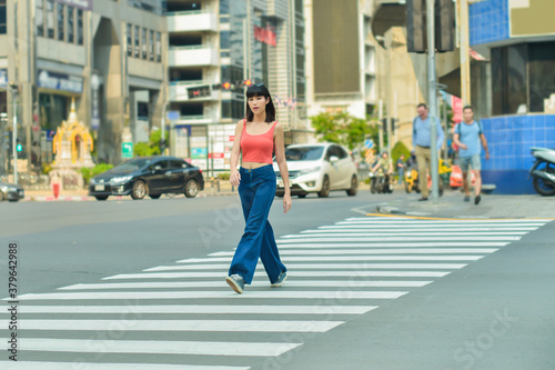 Beautiful asian woman crossing on crosswalk in Bangkok in sunny weather Fototapeta