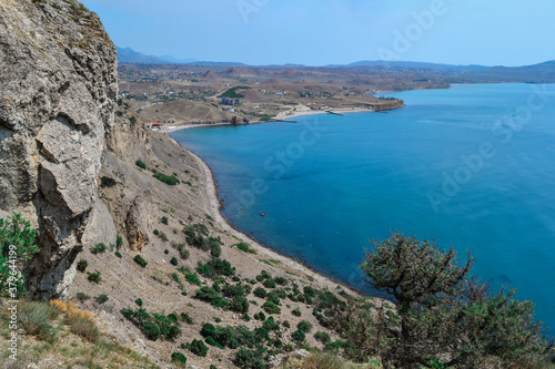 view of beautiful coast with green trees of bay of sea with blue water among hills and high mountains. Crimea, Russia, summer sunny landscape © SymbiosisArtmedia