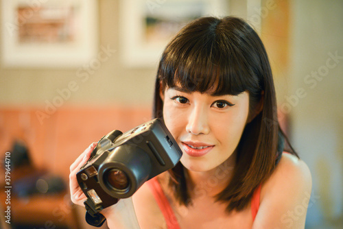 Beautiful cheerful young asian woman holding retro styled camera.
