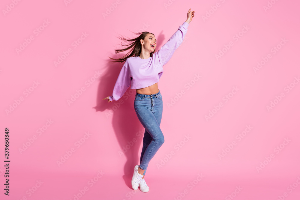 Full length photo of candid girl enjoy rejoice free time look good copyspace raise hand wear trendy pullover hair fly isolated over pastel color background
