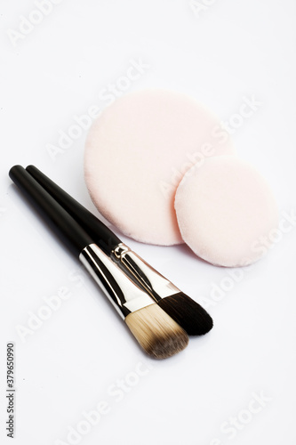 Powder puff and brushes on white background