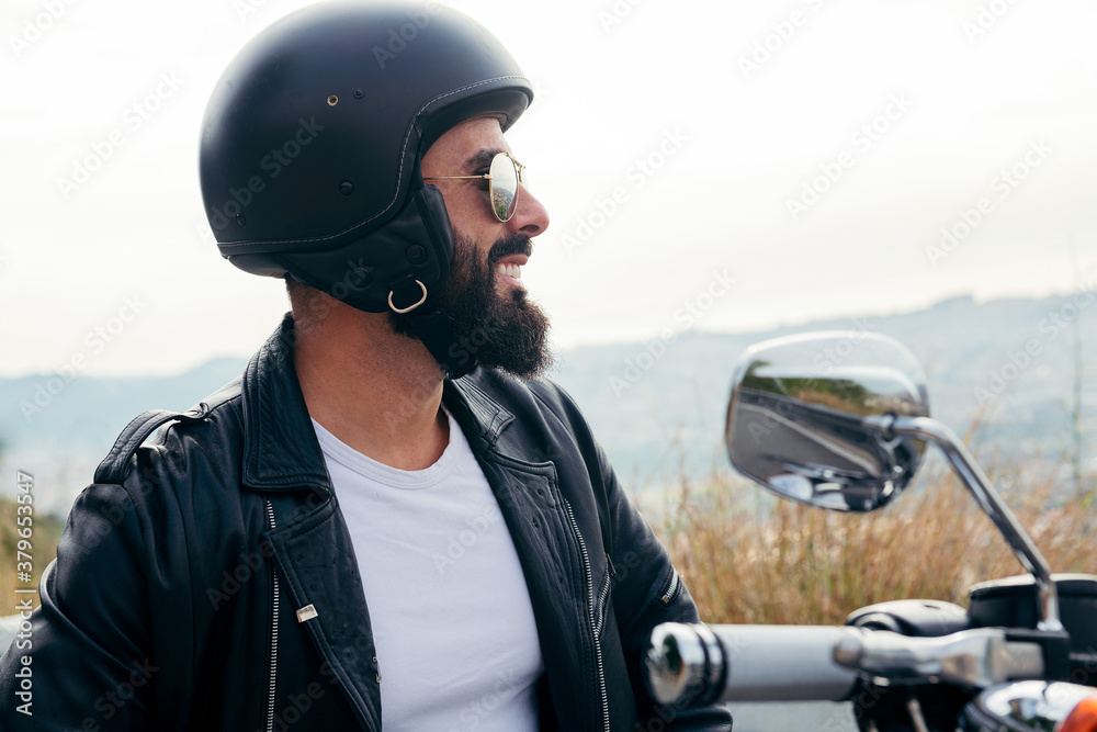 biker with helmet smiling sitting on his motorbike