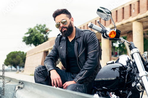 man sitting on a motorcycle by the side of a road