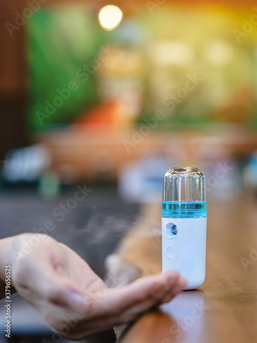Alcohol nano mist sprayer for hand cleaning to prevent the spread of the Corona virus  Covid-19  to serve customers at coffee shop. Modern health technology. New normal lifestyle. Selective focus