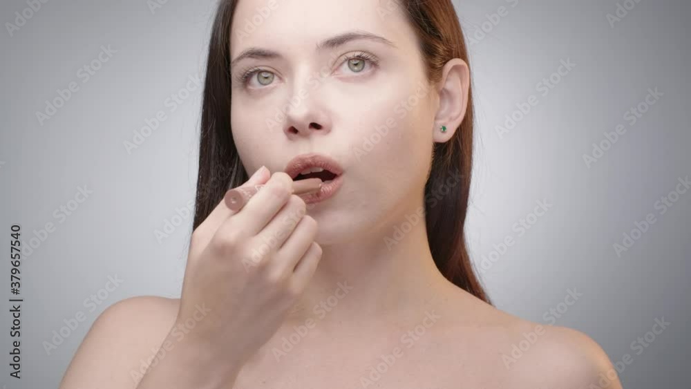Front view of young woman with long dark hair applies light brown lipstick with fingers in front of the mirror. Natural nude makeup. Getting ready for the date, preparing. Slow motion. 4k 50 fps Front view of young woman with long dark hair applies light brown lipstick with fingers in front of the mirror. Natural nude makeup. Getting ready for the date, preparing. Slow motion. 4k 50 fps