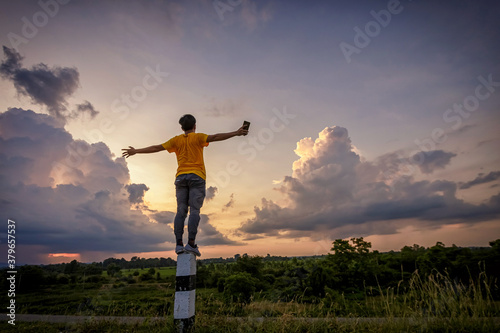 man standing in a field at sunset sky.