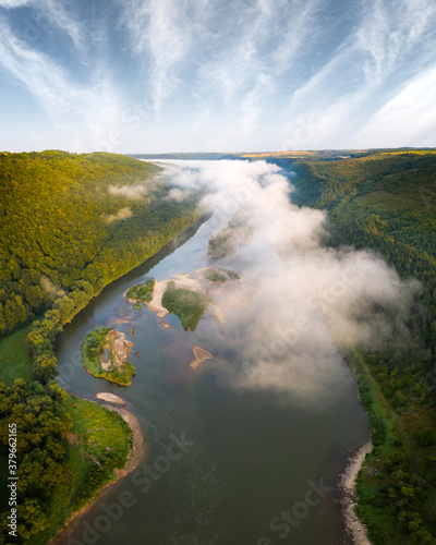 Flight through majestic foggy river and lush green forest at sunrise time. Landscape photography. Dnister, Ukraine, Europe