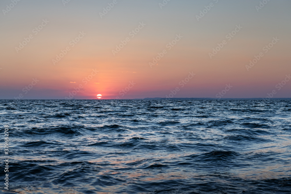 Sunset in the ocean with large sun dusk soft waves and red cloudy sky. Sea sunrise background. Landscape photography Sunset in the ocean with large sun dusk soft waves and red cloudy sky. Sea sunrise background. Landscape photography