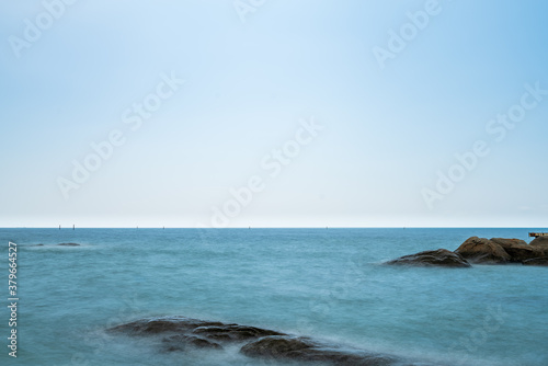 sea and beautiful blue sky with reef or rock in thailand at afternoon with copy space (long exposure)