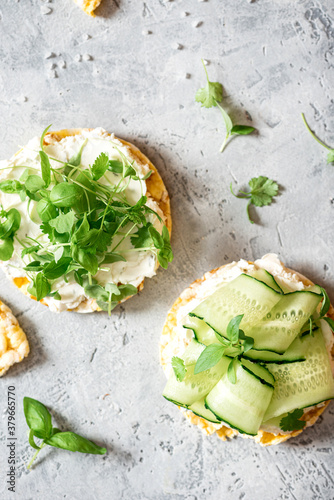 Tasty breakfast. Sandwich with crispbread, ricotta, cucumber and microgreens top view. Soft focus. Healthy vegetarian food. Sandwich with cream cheese and herbs on a concrete background.
