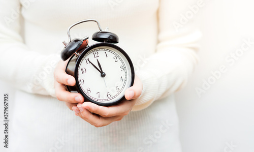 Close up shot of female hands holding a small clock.
