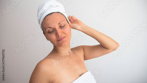Woman with her eyes closed and her head and body wrapped in fresh white towels on a white background. Negative space or copy space for text.