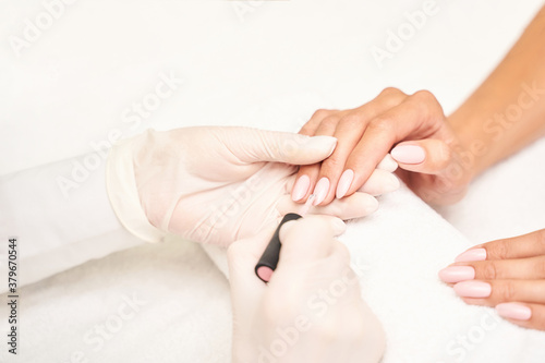 Beautiful salon procedure with pink manicure on towel background. For decoration design. Healthcare. Woman body care. Spa treatment. White background. Nail brush and polish.