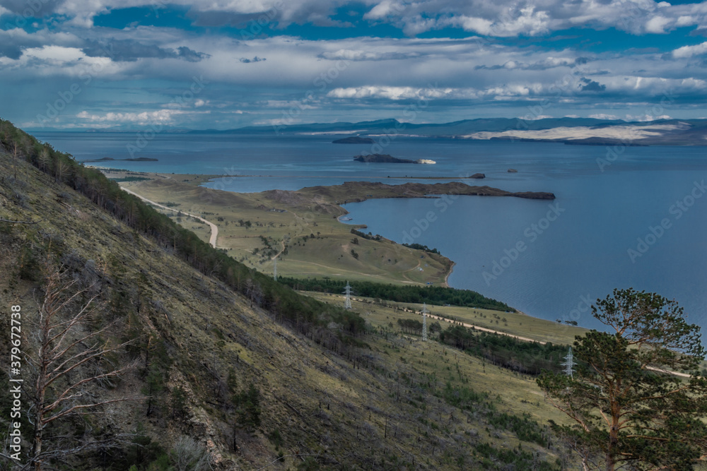 top view of the bay of lake Baikal with islands, peninsulas, clouds, blue sky, mountains and hill, before the rain