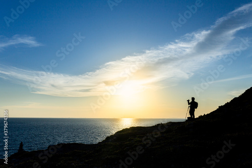 Silhouette of a nature photographer framing a shot, taking pictures at sunset on the beach