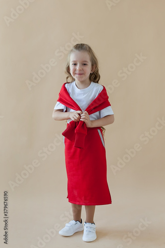 A little girl in a red suit poses on a colored background. Fashionable children's clothing.