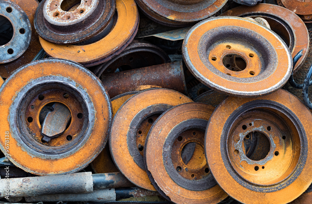close up on old used and rusty car wheel rotors in a scrapyard