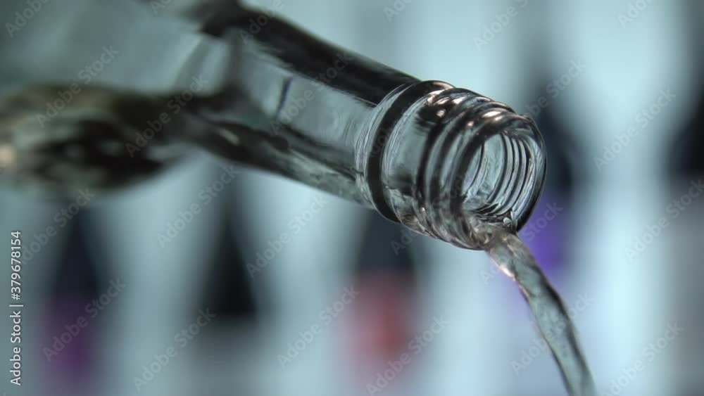 White wine pouring from bottle close up shot. Wine collection as background. Slow motion shot. White wine pouring from bottle close up shot. Wine collection as background. Slow motion shot.