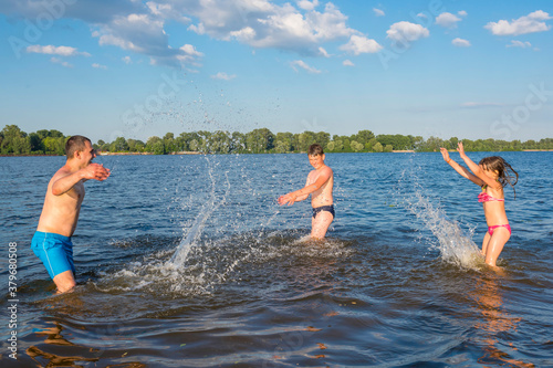 Happy family have fun playing in the river on summer vacation. Family outdoor sports games. Active healthy lifestyle concept. © Andrii