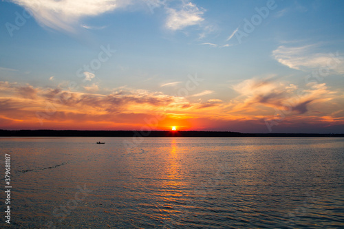 Sunset on the lake. A fisherman is fishing from a boat