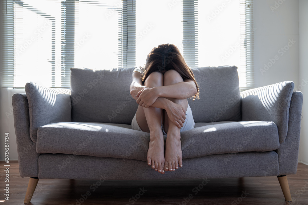 Teenager Asian girl with depression sitting alone on the sofa in the room. Teenager Asian girl with depression sitting alone on the sofa in the room.