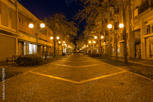 Walking Illuminated night Grado town. Deserted streets of touristic italian city in winter at night.